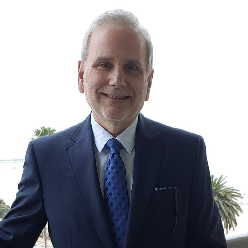 Smiling middle‑aged man in dark suit and blue tie